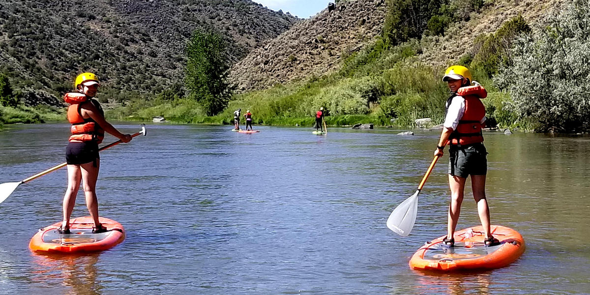 People standing on paddle boards in the Rio Grande River