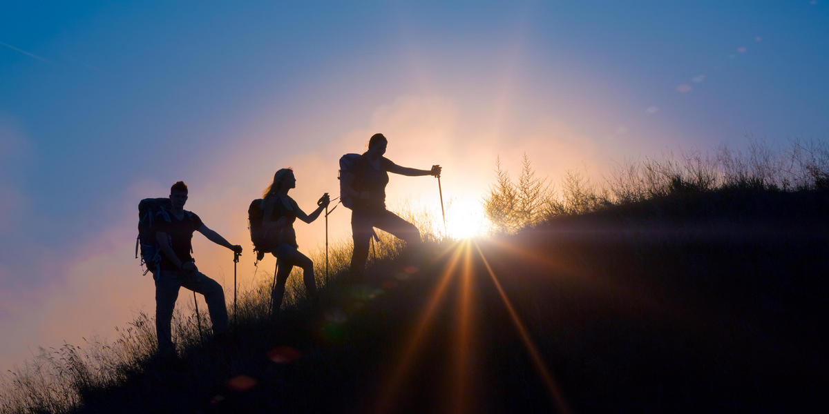 3 hikers walking with sun in background